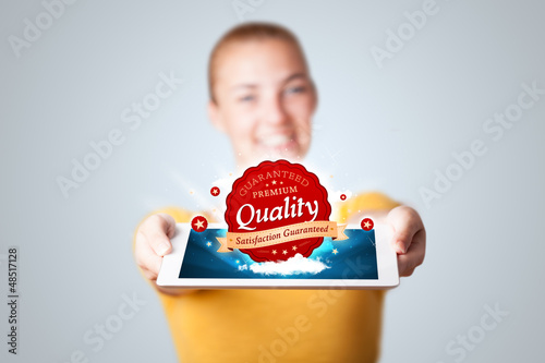 Photo: woman holding tablet with red quality label in clouds woman holding tablet with red quality label in clouds