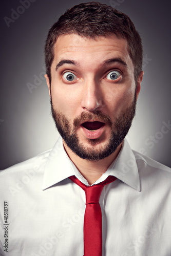 Photo: surprised man over grey background surprised man over grey background