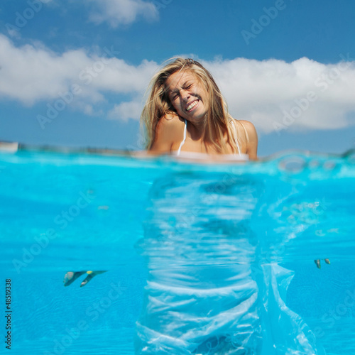 Photo: Laughing woman portrait while entering in swimming pool. Laughing woman portrait while entering in swimming pool.