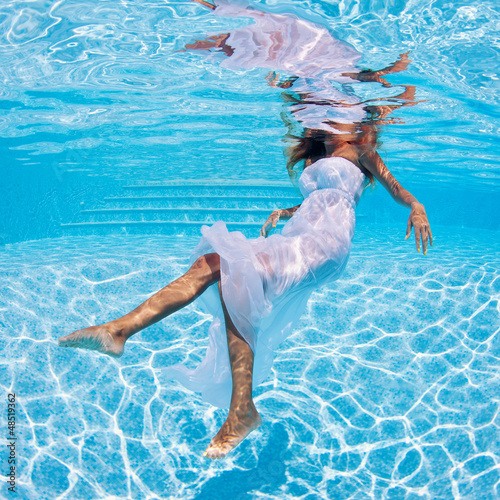 Photo: Underwater girl portrait with white dress in swimming pool. Underwater girl portrait with white dress in swimming pool.