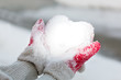 Hands hold snow like a heart