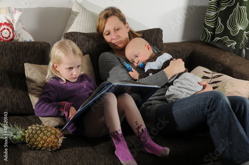 Photo: Mutter ließt Kindern auf dem Sofa eine Geschichte vor Mutter ließt Kindern auf dem Sofa eine Geschichte vor