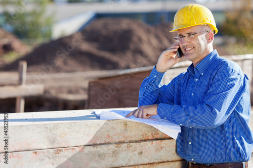 Photo: bauleiter mit handy und bauplan bauleiter mit handy und bauplan
