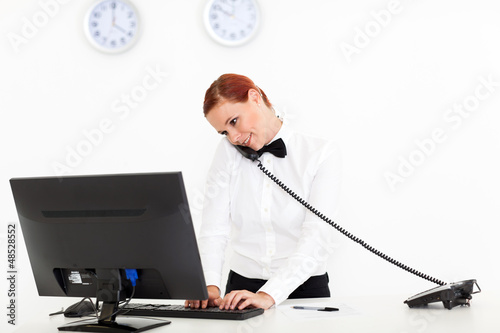 Photo: hotel receptionist talking on phone while checking on computer hotel receptionist talking on phone while checking on computer