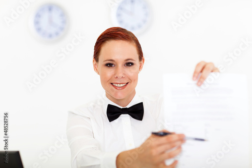 Photo: friendly hotel receptionist giving form for signing friendly hotel receptionist giving form for signing