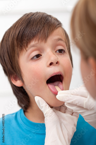 Photo: Boy showing her throat to health professional Boy showing her throat to health professional