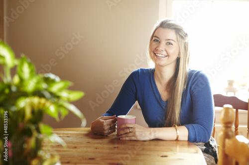 Photo: Young woman sitting at table smiling Young woman sitting at table smiling