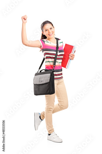 Photo: Full length portrait of a happy female student holding notebooks Full length portrait of a happy female student holding notebooks