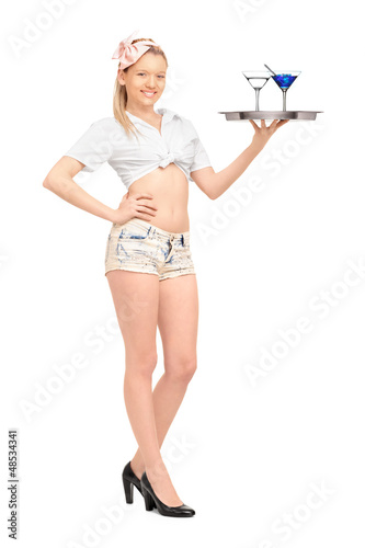 Photo: Young waitress in short pants holding a tray with two cocktails Young waitress in short pants holding a tray with two cocktails