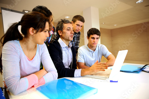 Photo: Teacher with students in class working on laptop Teacher with students in class working on laptop