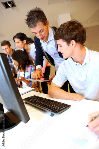 Photo: Adult man helping student in classroom Adult man helping student in classroom