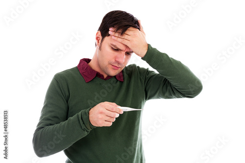 Photo: Young man suffering from a cold and checking his temperature on Young man suffering from a cold and checking his temperature on