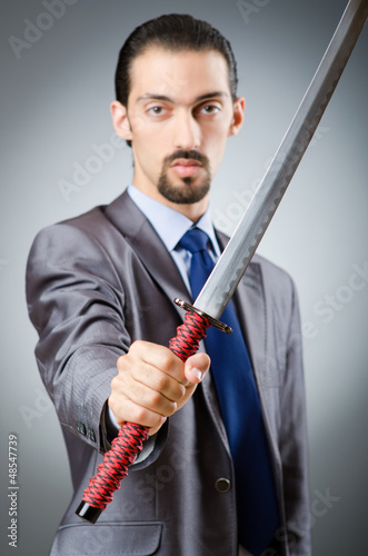 Photo: Angry businessman with sword in dark room Angry businessman with sword in dark room
