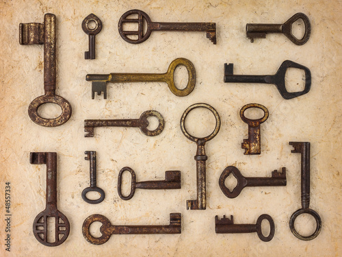 Photo: Different antique keys on a retro paper background Different antique keys on a retro paper background