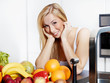 Pretty girl in the kitchen eating healthy food to lose weight