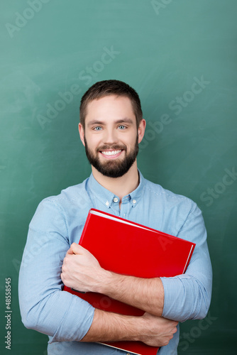 Photo: lächelnder student mit aktenordner vor der tafel lächelnder student mit aktenordner vor der tafel