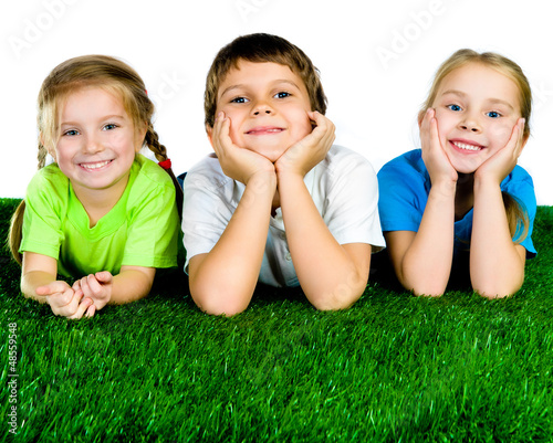 Photo: boy and girls lying on a green grass boy and girls lying on a green grass