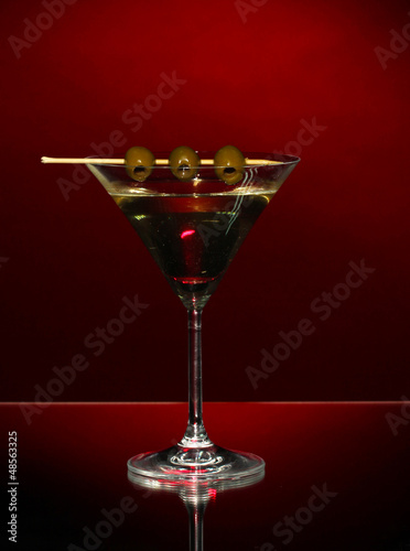 Photo: Martini glass and olives on dark background Martini glass and olives on dark background