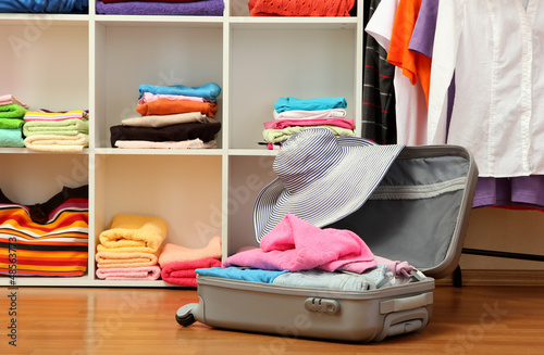 Photo: Open silver suitcase with clothing in room Open silver suitcase with clothing in room