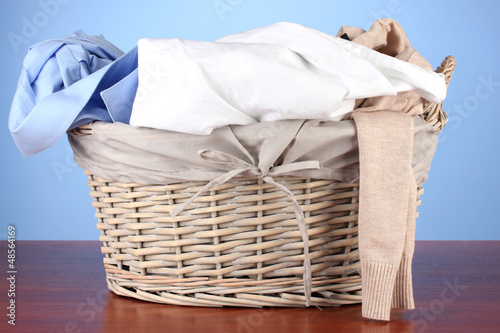 Photo: Bright clothes in laundry basket,on color background Bright clothes in laundry basket,on color background