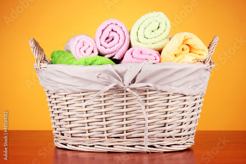 Photo: Colorful towels in basket on color background Colorful towels in basket on color background