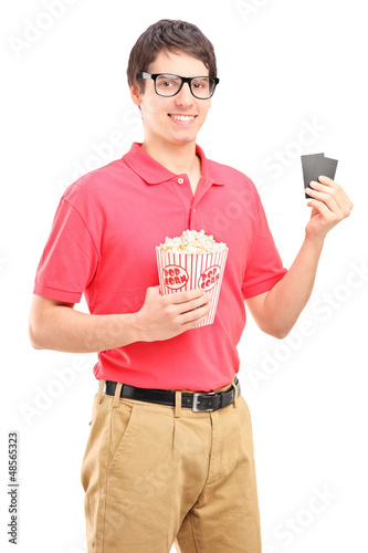 Photo: Smiling man holding a popcorn and two tickets for cinema Smiling man holding a popcorn and two tickets for cinema