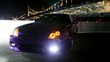 Car stand with parking lights blinks at background of bridge