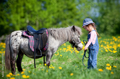 Photo: Child and small horse in the field at spring going to ride. Child and small horse in the field at spring going to ride.
