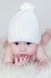 The thoughtful four-months baby in a white knitted hat