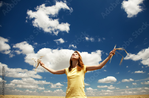 Photo: Redhead girl at wheat field in summer day. Redhead girl at wheat field in summer day.