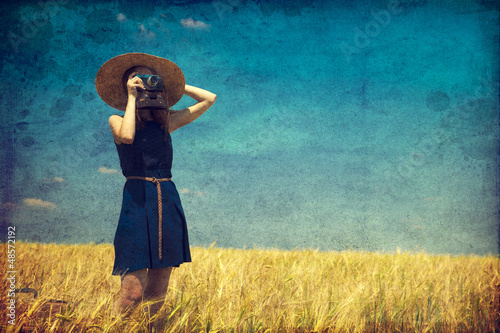 Photo: Redhead girl at spring field with retro camera. Redhead girl at spring field with retro camera.