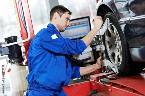 Photo: auto mechanic at wheel alignment work with spanner auto mechanic at wheel alignment work with spanner