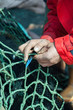 Fisher darning fish seine with net needle