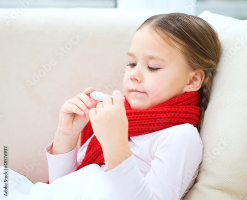 Photo: Ill little girl is reading thermometer Ill little girl is reading thermometer