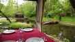 Dining table is set in bower ashore of small pond