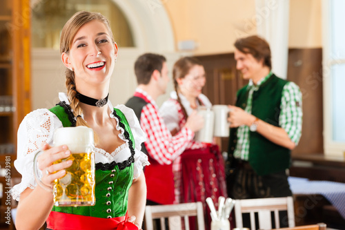 Photo: Young people in traditional Bavarian Tracht in restaurant or pub Young people in traditional Bavarian Tracht in restaurant or pub