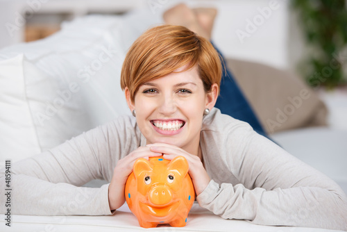 Photo: lachende junge frau mit sparschwein lachende junge frau mit sparschwein