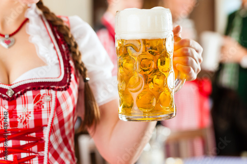 Photo: Young people in traditional Bavarian Tracht in restaurant or pub Young people in traditional Bavarian Tracht in restaurant or pub