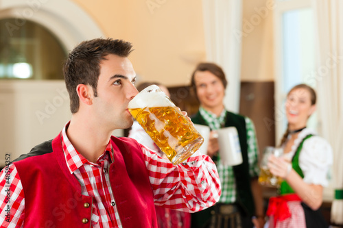 Photo: Young people in traditional Bavarian Tracht in restaurant or pub Young people in traditional Bavarian Tracht in restaurant or pub