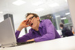 Photo: bored yawning businessman with laptop in the office bored yawning businessman with laptop in the office