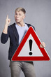 Man holding warning sign with exclamation mark.