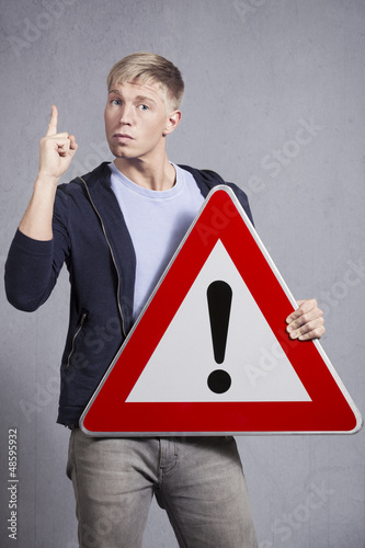 Photo: Man holding warning sign with exclamation mark. Man holding warning sign with exclamation mark.