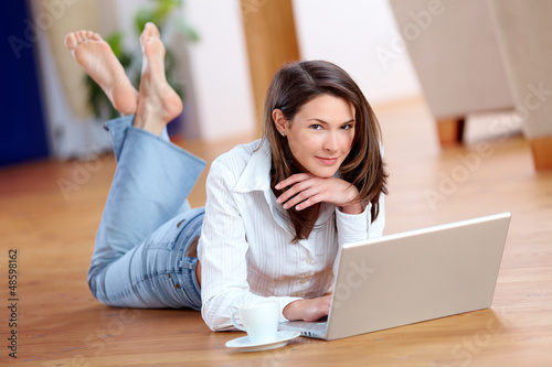 Photo: Beautiful young woman with laptop on the floor Beautiful young woman with laptop on the floor