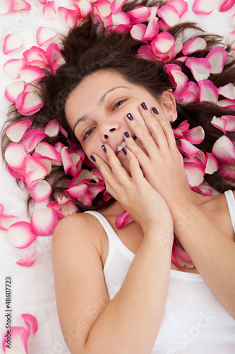 Photo: Rose petals surround a woman laying on a bed Rose petals surround a woman laying on a bed