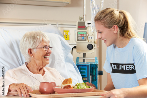 Photo: Teenage Volunteer Serving Senior Female Patient Meal In Hospital Teenage Volunteer Serving Senior Female Patient Meal In Hospital