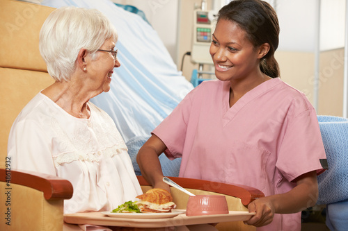 Photo: Nurse Serving Meal To Senior Female Patient Sitting In Chair Nurse Serving Meal To Senior Female Patient Sitting In Chair