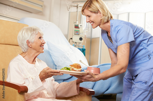 Photo: Nurse Serving Meal To Senior Female Patient Sitting In Chair Nurse Serving Meal To Senior Female Patient Sitting In Chair