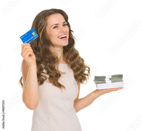 Photo: Happy young woman holding credit card and money packs Happy young woman holding credit card and money packs