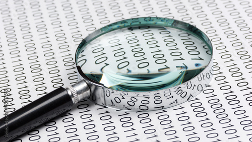 Photo: magnifying glass on a binary code magnifying glass on a binary code