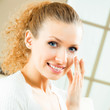 Photo: Happy smiling woman applying creme, indoor Happy smiling woman applying creme, indoor